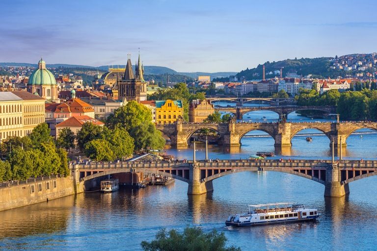 The Vltava River and Charles Bridge beneath Prague's historic skyline at sunset