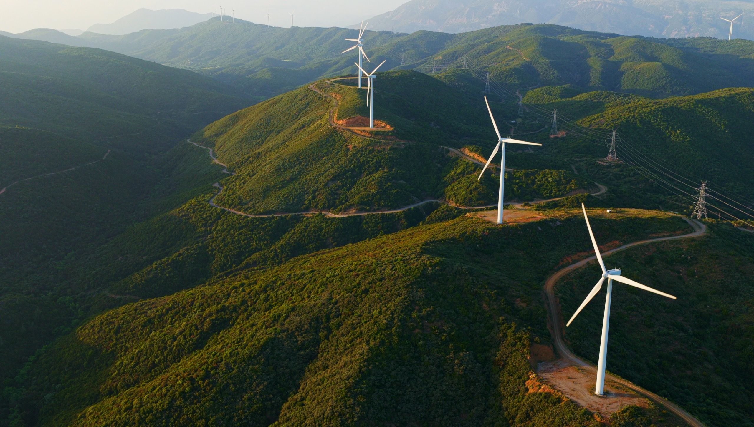 Wind turbines on green hillsides at sunset