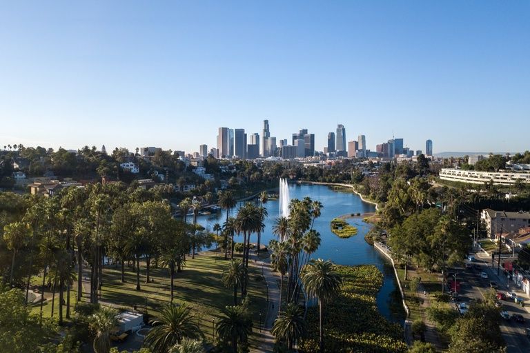 Der Springbrunnen im Echo Park Lake und Palmen unter der Skyline von Downtown Los Angeles