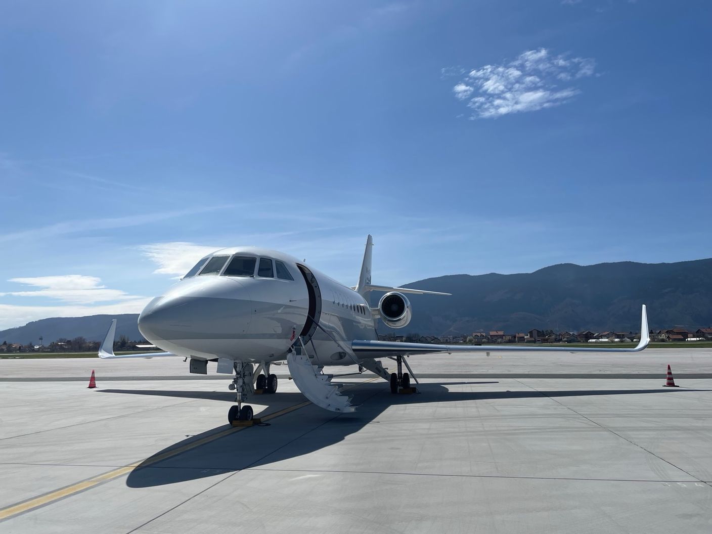 Jet privé stationné sur l'aire de trafic, montagnes en arrière-plan sous un ciel bleu