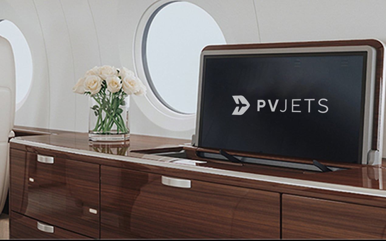 Private jet cabin with the PVJets logo displayed on a screen