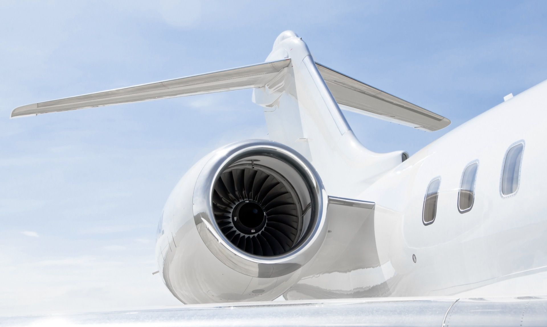 Close-up of a private jet engine and wing against a blue sky