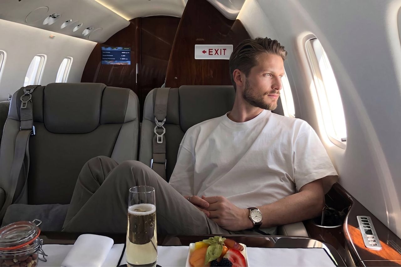 A man relaxing in a private jet cabin with a glass of champagne