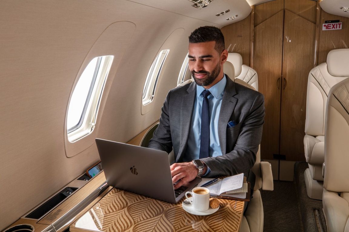 A business traveller working on a laptop inside a private jet